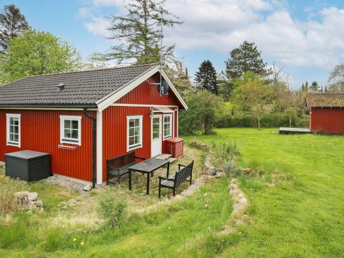 a red tiny house with a bench in a field at 6 person holiday home in Dronningm lle in Gilleleje