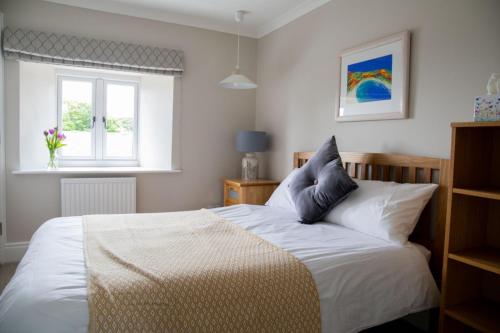 a bedroom with a bed with white sheets and a window at Tresithick Vean Bed and Breakfast in Truro