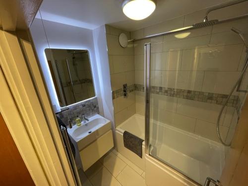 ein Bad mit einem Waschbecken und einer Dusche in der Unterkunft Spacious 2-Bedroom Flat Near Surbiton Station in Surbiton