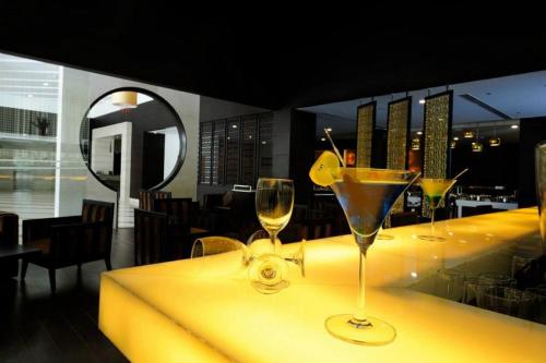 a bar with three wine glasses on a yellow counter at Gurmon Hotels Sohna Road Gurugram, a member of Radisson Individuals in Sohna