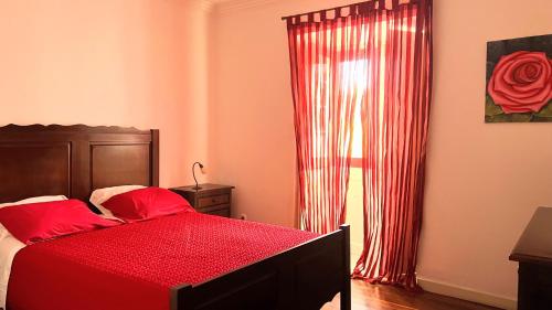 a bedroom with a bed with red sheets and a window at Casa da Japoneira in Horta