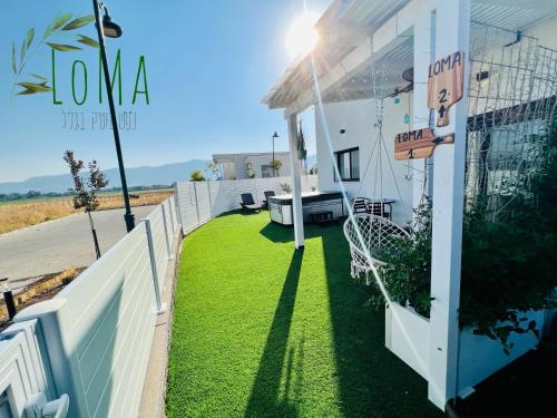 a yard with green grass on the side of a house at LOMA in Hagoshrim