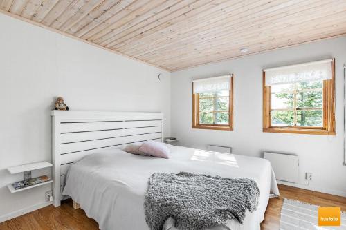 a bedroom with a white bed and two windows at Ekudden. Idylliskt nära sjö. Egen strand. in Rimforsa