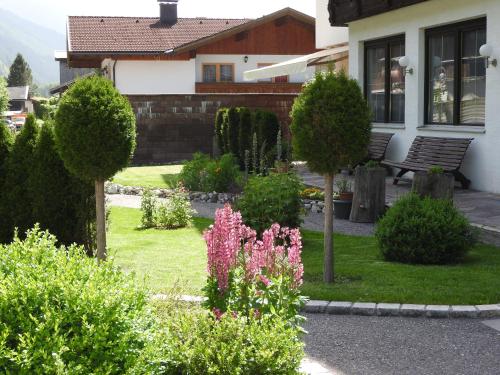 a garden with flowers and a bench in front of a house at Pension Elmerhof in Elmen