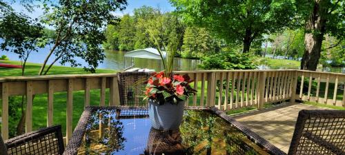 un jarrón con flores en una mesa en una cubierta en Large 1 BR Cottage, KING BED on the Lake, en Paw Paw