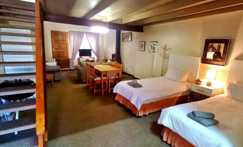 a room with two beds and a living room with a table at Villa Moria Peace Cottage in Dullstroom