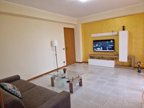 salon z kanapą i telewizorem na ścianie w obiekcie L'Isola e i Faraglioni house w mieście Aci Trezza