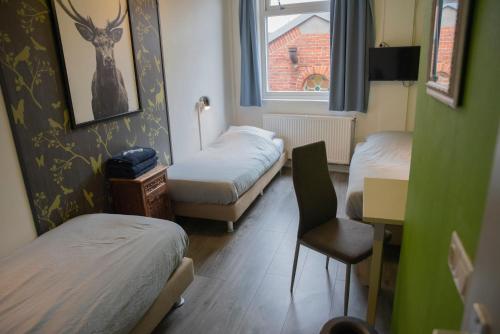 a room with two beds and a chair and a window at Simplon Hostel in Groningen