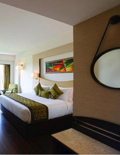 a hotel room with a large bed and a mirror at Gurmon Hotels Sohna Road Gurugram, a member of Radisson Individuals in Sohna
