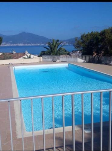 une grande piscine bleue avec l'océan en arrière-plan dans l'établissement Porticcio très joli T2 climatisé & grande terrasse à 1km de la plage, à Porticcio