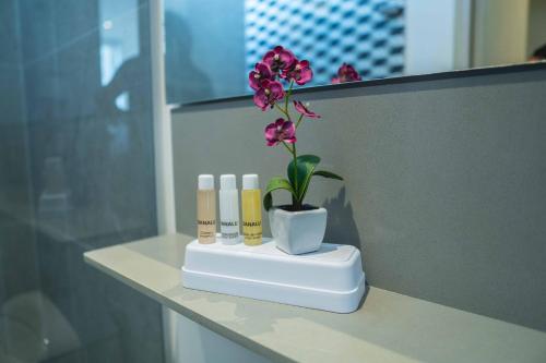 a flower in a vase on a shelf with three candles at Suite de lujo Distrito 90 in Barranquilla