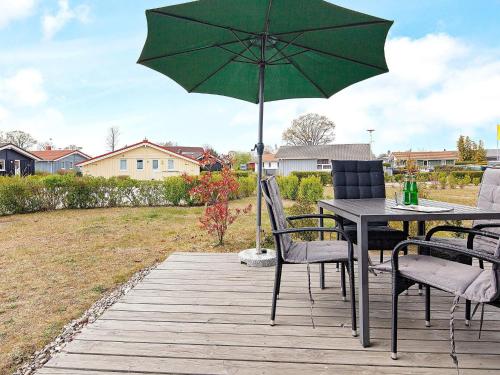 einen Tisch mit einem grünen Sonnenschirm auf einer Terrasse in der Unterkunft 4 person holiday home in GROEMITZ in Grömitz