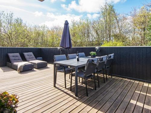 a wooden deck with a table and chairs and an umbrella at 6 person holiday home in Hemmet in Falen