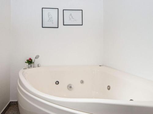 a white bath tub in a bathroom with two pictures on the wall at 6 person holiday home in Hemmet in Falen