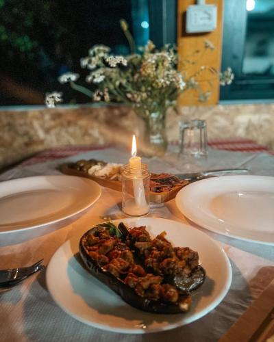 a table with two plates of food and a candle at Villa Gjeçaj Guesthouse and Restaurant in Theth