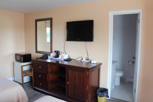 1 dormitorio con tocador y TV en la pared en Save Inn en Kincardine