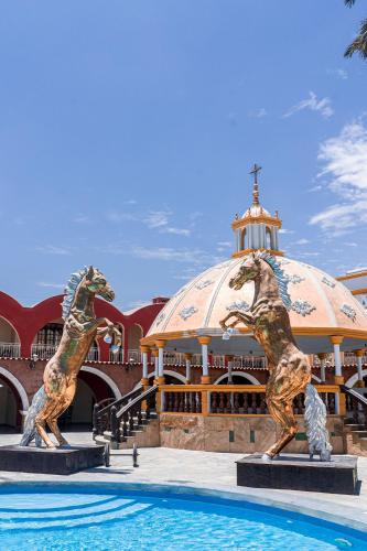 two statues in front of a building with a pool at Macacona Hacienda Hotel in Ica