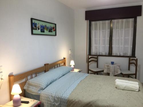 a bedroom with two beds and a window and two chairs at Pensión El Pozo in Cudillero