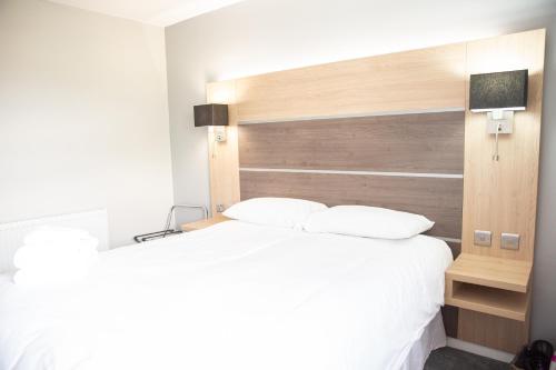 a bedroom with a large white bed with a wooden headboard at Granary Villa in Kidderminster