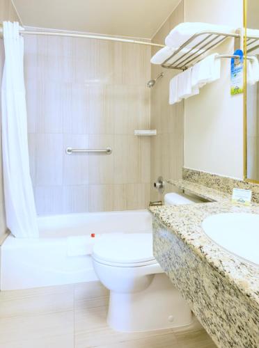 a bathroom with a toilet and a sink and a tub at Days Inn by Wyndham Santa Monica in Los Angeles