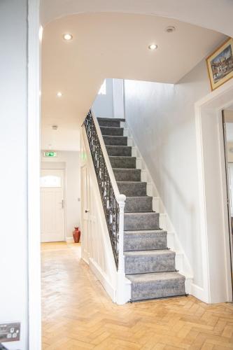 a staircase in a home with white walls and wood floors at Granary Villa in Kidderminster