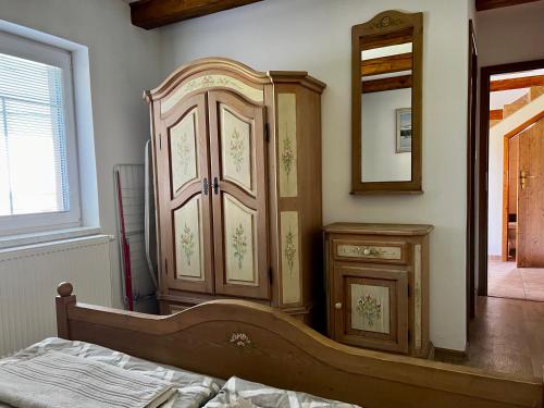 a bedroom with a wooden cabinet and a mirror at Chalupa Kadov in Sněžné