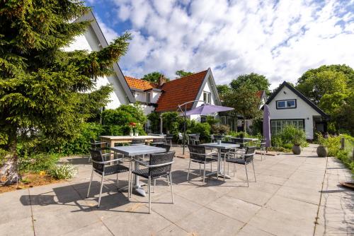 a patio with tables and chairs in front of a house at Villa de Hazelaar in Schoorl