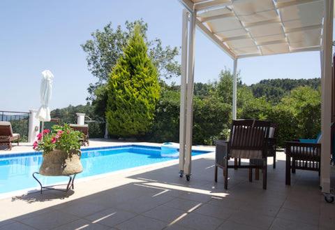 eine Terrasse mit Stühlen und einen Pool mit Pavillon in der Unterkunft Skopelos Country Villas in Panormos Skopelos