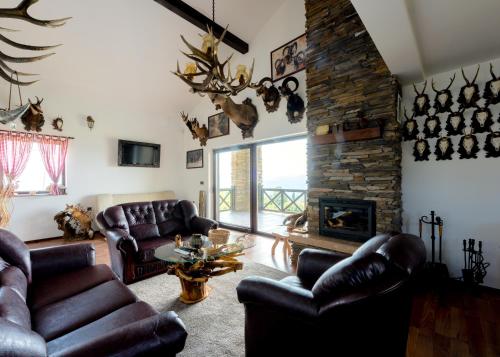 a living room with leather furniture and a stone fireplace at Vila Pellegrini in Arandjelovac