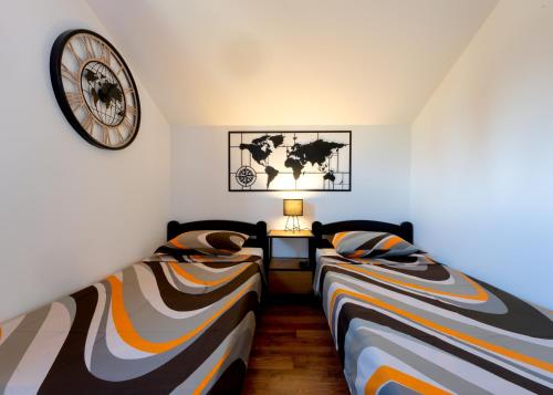 two beds in a room with a clock on the wall at Vila Pellegrini in Arandjelovac