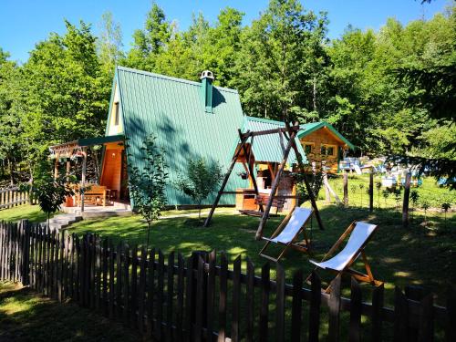 a house with a playground and two chairs in the yard at Koliba Pčelica 2 in Bijelo Polje