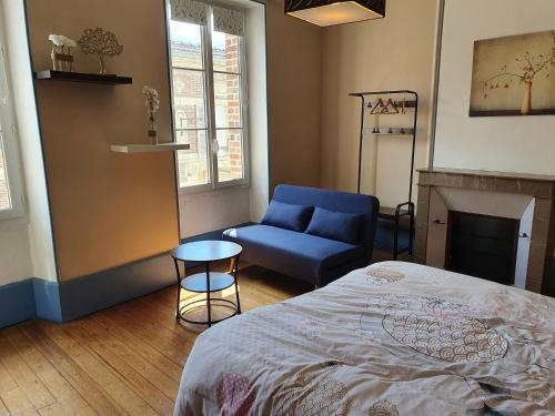 a bedroom with a bed and a blue chair at La Cour des Marotiers in Mareuil-sur-Ay