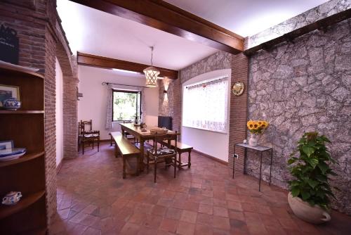 une salle à manger avec une table et un mur en briques dans l'établissement Villa Caterina, alle pendici del Vulcano Etna, à Viagrande
