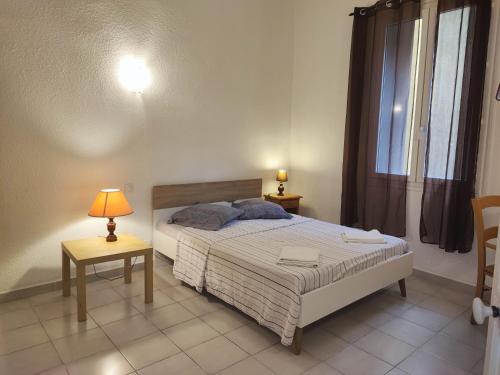 une chambre avec un lit et deux tables et une fenêtre dans l'établissement le jardin botanique, à Perpignan