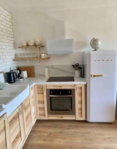 a kitchen with a white refrigerator and wooden cabinets at Valberg 8 couchages cocon familial in Guillaumes