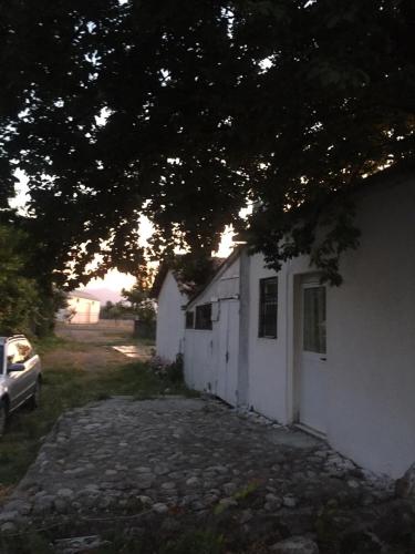 a white building with a car parked next to it at Anza Camping in Shkodër