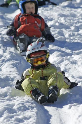 two children are sitting in the snow at Clubhotel Götzens in Innsbruck