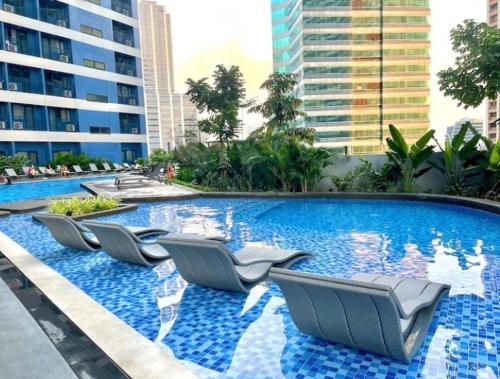 a row of lounge chairs in a swimming pool at Luxurious Condotel at the heart of Makati in Manila