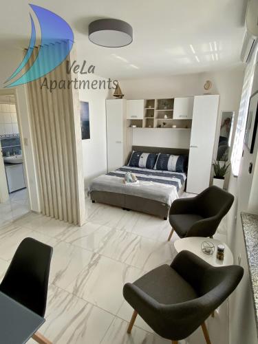 a bedroom with a bed and chairs in a room at VeLa Apartments in Ičići