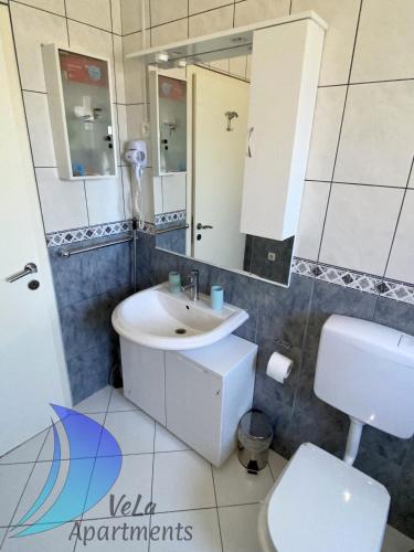 a bathroom with a sink and a toilet and a mirror at VeLa Apartments in Ičići