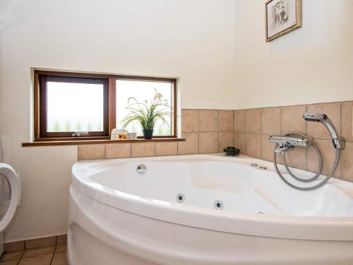 a large white tub in a bathroom with a window at 8 person holiday home in Ulfborg in Thorsminde