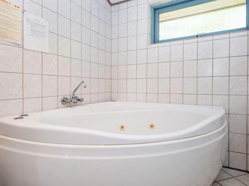 eine weiße Badewanne in einem weiß gefliesten Bad in der Unterkunft 8 person holiday home in B rkop in Børkop