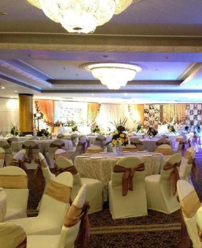 a banquet hall with white chairs and tables and chandeliers at Park Plaza, Ludhiana in Ludhiana