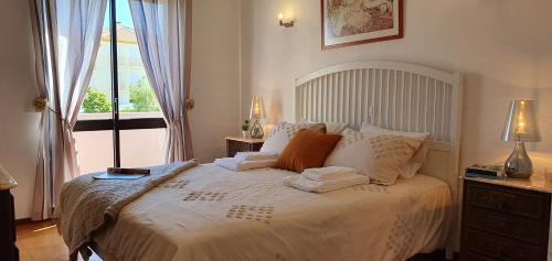 um quarto com uma grande cama branca e uma janela em Villa charmosa V2 junto à praia e à Marina de Vilamoura em Quarteira