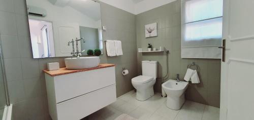 a white bathroom with a toilet and a sink at Villa charmosa V2 junto à praia e à Marina de Vilamoura in Quarteira