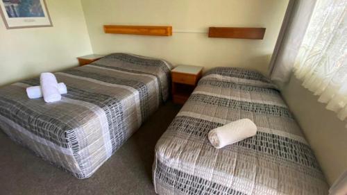 two beds in a hotel room with towels on them at Bucketts Way Motel Gloucester in Gloucester