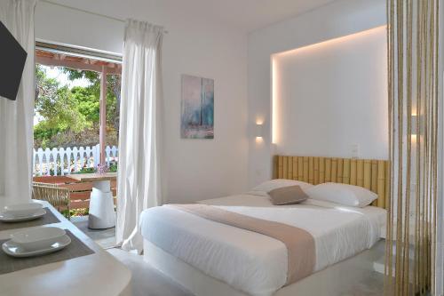 - une chambre blanche avec un grand lit et une fenêtre dans l'établissement Niriis Studio 7 Batsi Andros, à Batsi
