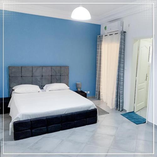 a blue bedroom with a large bed and a blue wall at Nalabba in Dakar