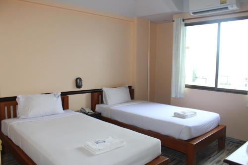 two beds in a room with a window at Grand Mansion Hotel in Krabi town