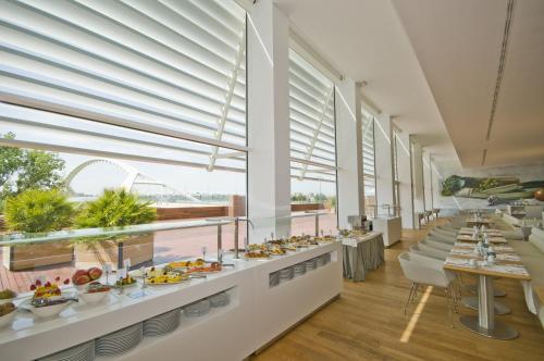 a buffet line with food in a large room with windows at Hotel Hiberus in Zaragoza